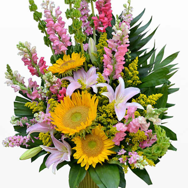 Mixed bouquet with sunflowers, lilies, and pink snapdragons in a vase