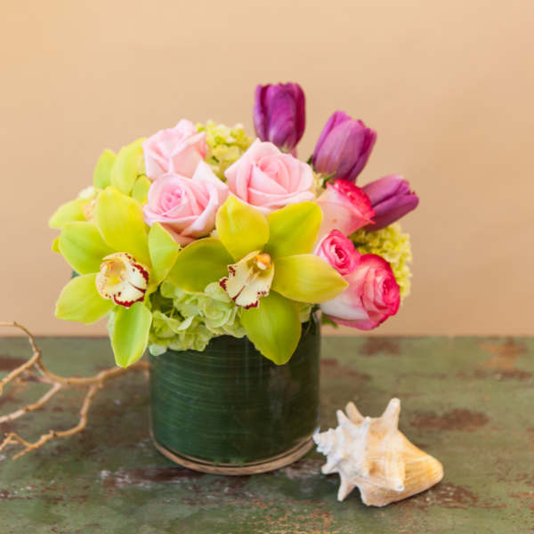 Pink roses and green orchids arranged in a dark vase