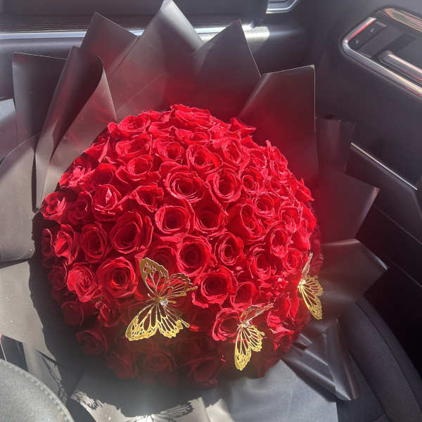 Large dome bouquet of red roses wrapped in black paper with gold butterfly accents