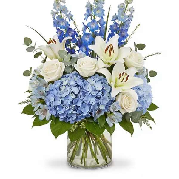 Blue hydrangeas, white lilies, and roses in a glass vase