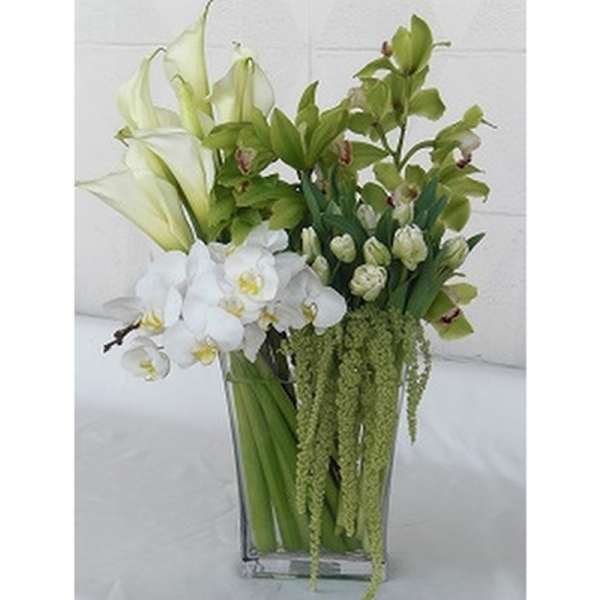 White orchids and green calla lilies in a clear glass vase