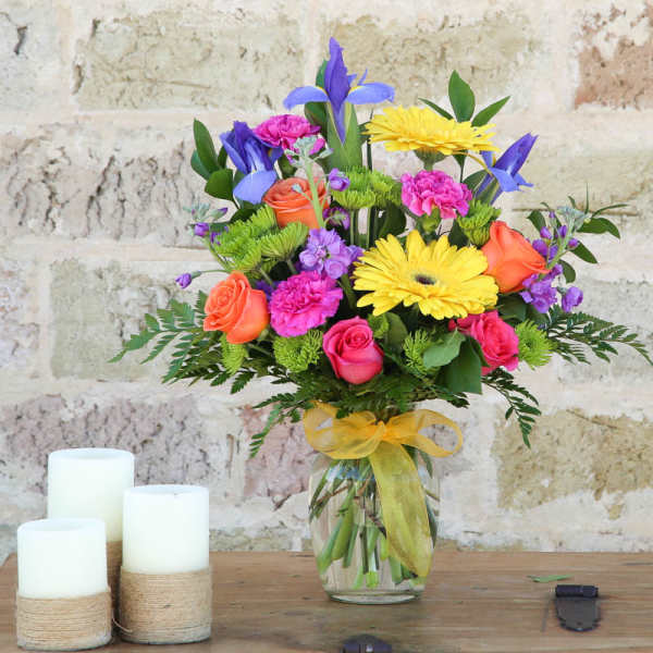 Colorful mixed bouquet in a glass vase with a yellow ribbon