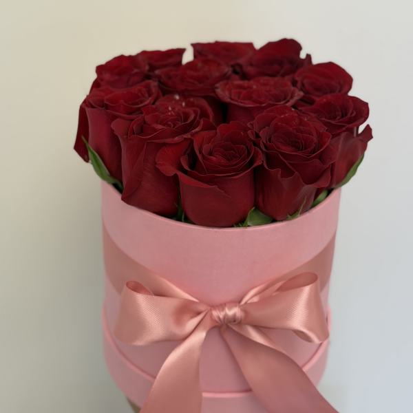 Bouquet of red roses in a pink hat box with a satin ribbon