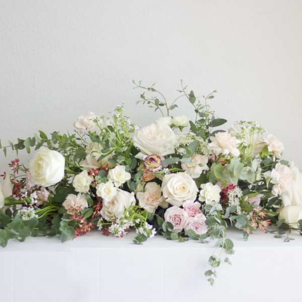 Low floral arrangement with white and blush roses on a table