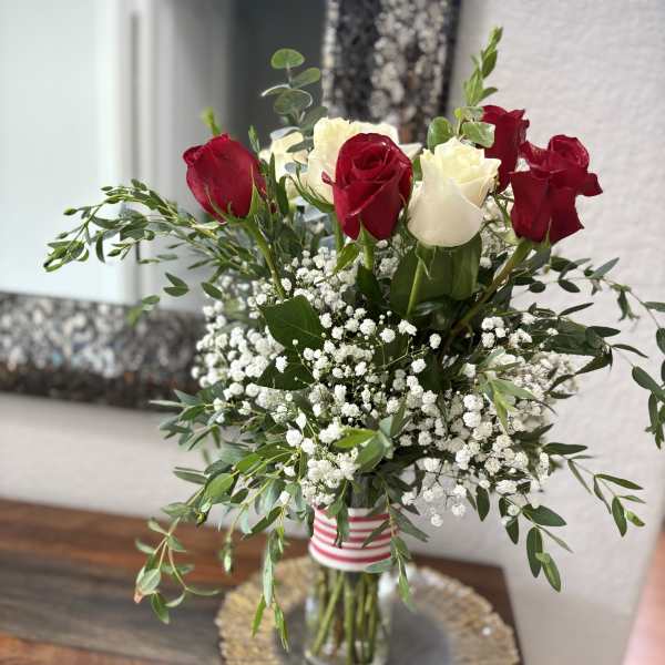 Red and white roses in a glass vase with baby's breath