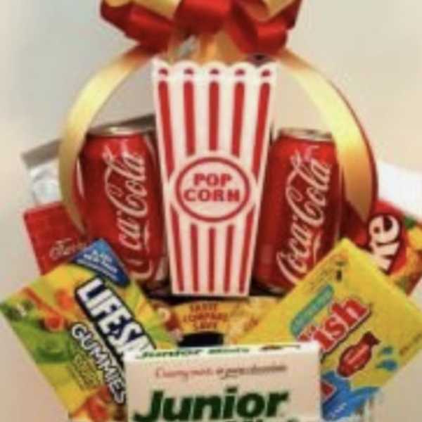 Popcorn bucket gift basket with candy and soda cans topped by a red-and-gold bow