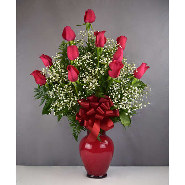 Pink roses in a red vase with baby's breath and a red bow