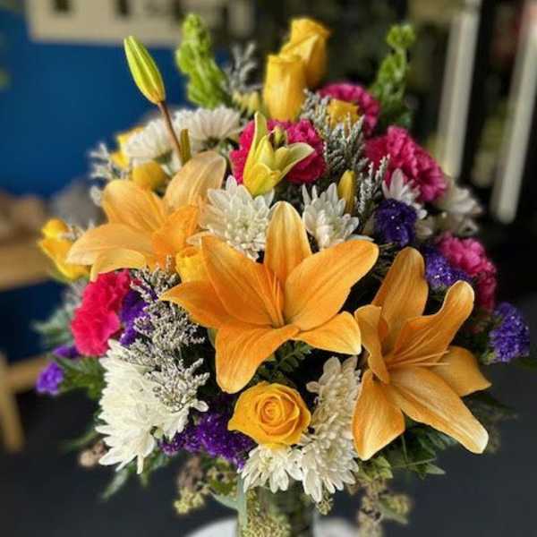 Colorful bouquet with lilies, roses, and chrysanthemums in a glass vase