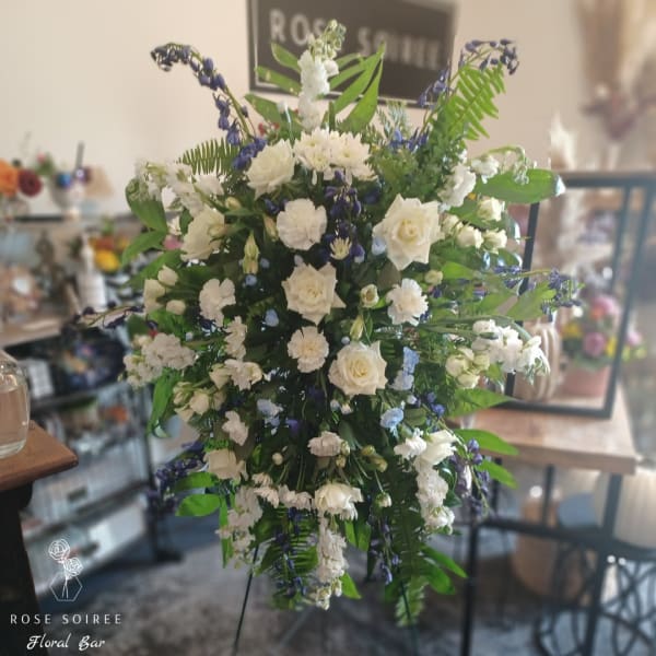 Tall white and blue floral arrangement with roses and mixed blooms