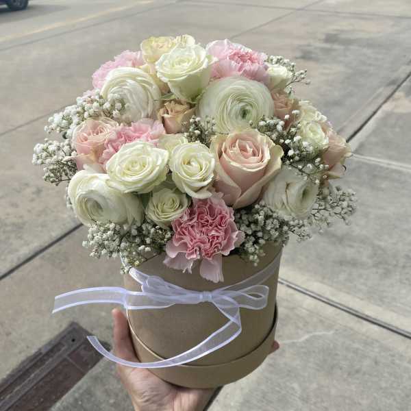 Round bouquet of pink and white roses in a ribbon-tied hat box