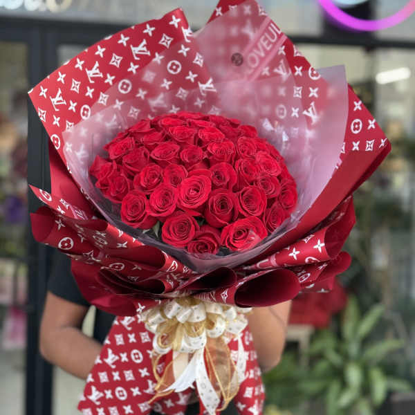 Large bouquet of red roses wrapped in patterned red paper