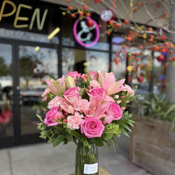 Pink roses and lilies arranged in a clear glass vase