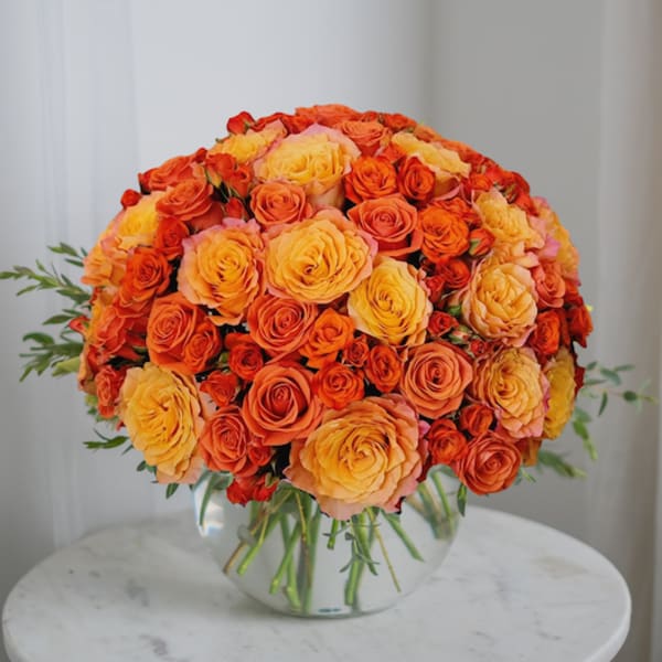 Bouquet of orange and yellow roses in a clear glass vase