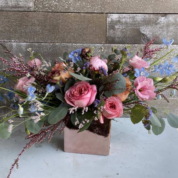 Pink roses and blue flowers in a square metallic vase