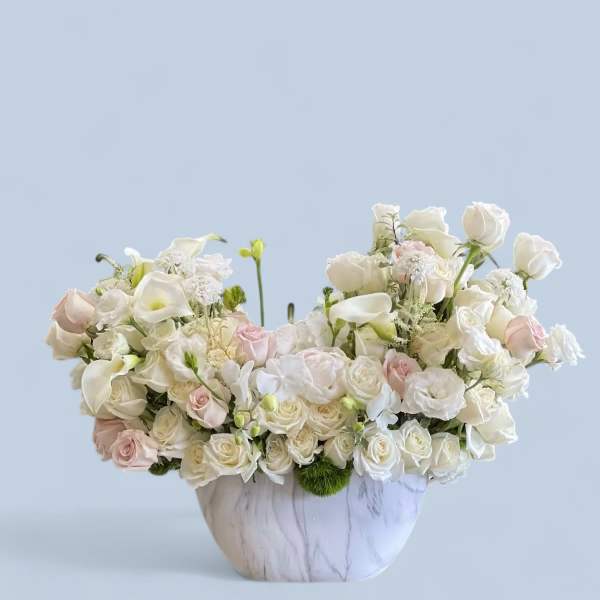 White and blush roses with calla lilies in a marble-look vase