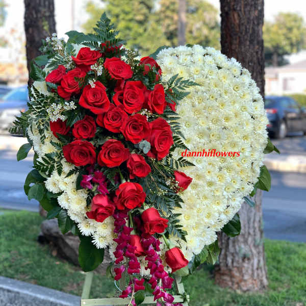 Heart-shaped floral tribute with red roses and white chrysanthemums on an easel