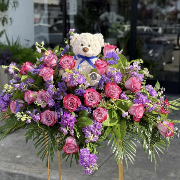 Pink and purple rose arrangement with a teddy bear centerpiece