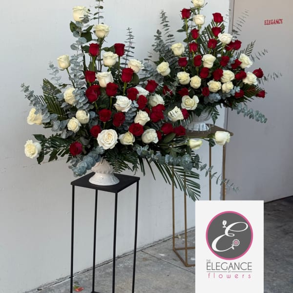 Large red and white rose arrangements in white vases on tall stands