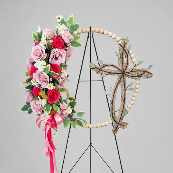 Floral cross wreath with pink roses and white daisies on a stand