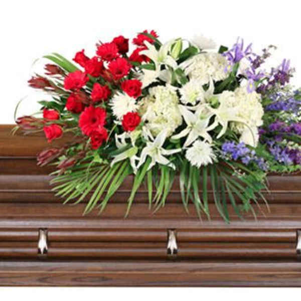 Floral casket spray with red, white, and purple flowers on a wooden casket