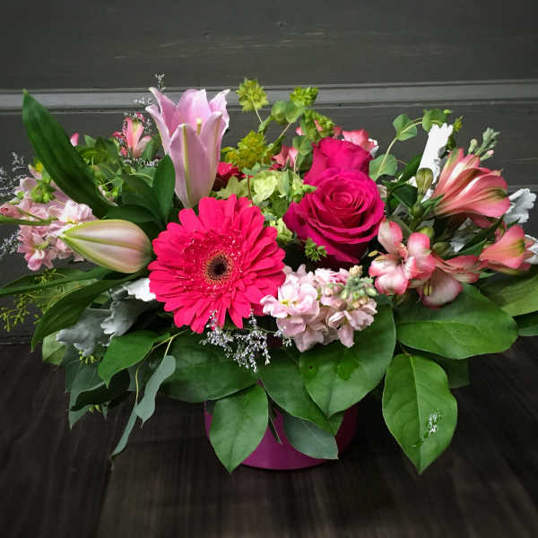 Mixed pink floral arrangement in a round pink container