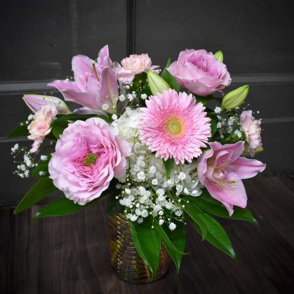 Pink lilies and gerbera daisies arranged in a glass vase