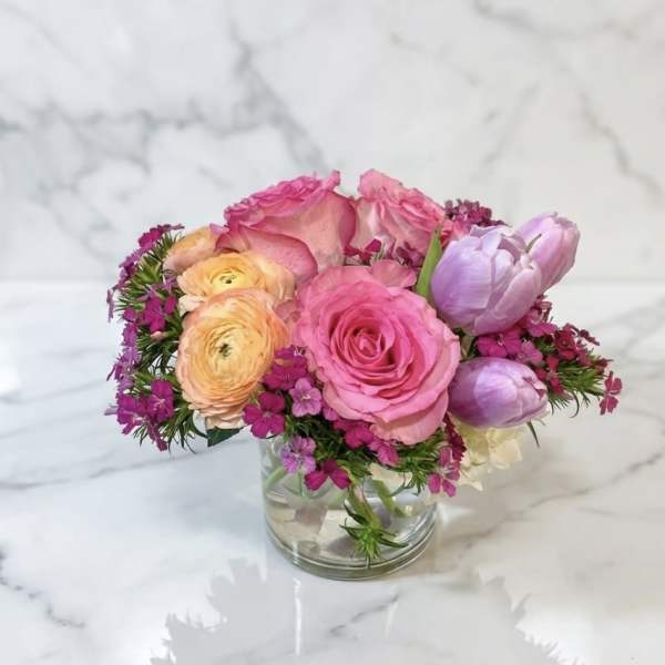 Pink and peach flowers arranged in a clear glass vase