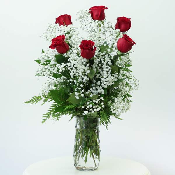 Red roses arranged with white baby's breath in a glass vase
