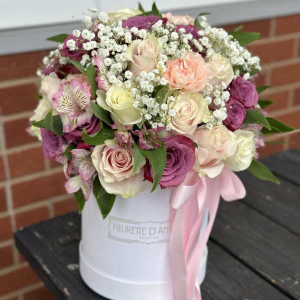 Pink and cream rose bouquet in a white hat box with a pink ribbon
