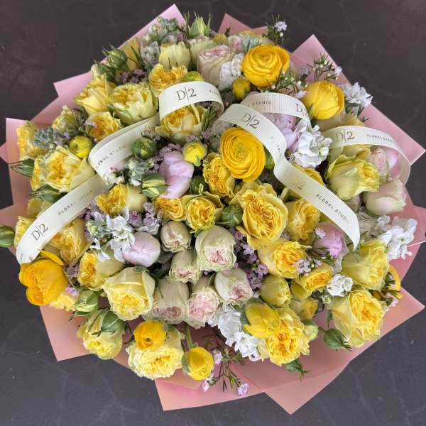 Large bouquet of yellow and pale pink roses wrapped in pink paper