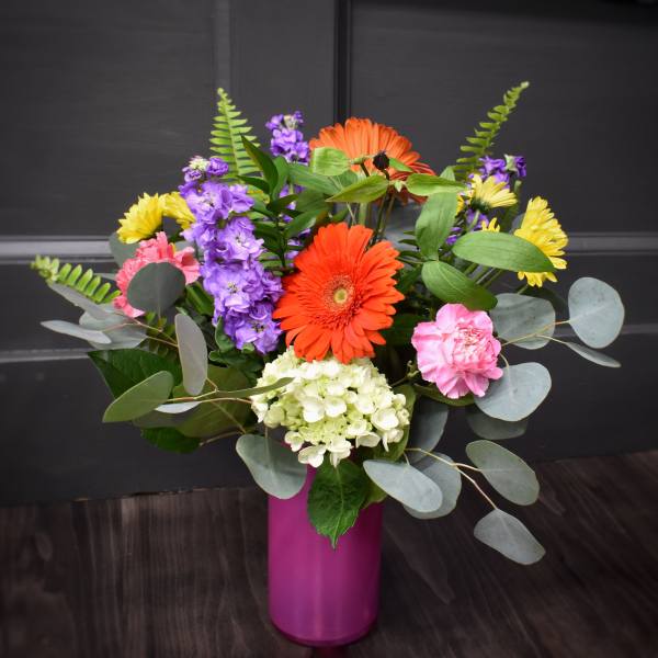Colorful mixed bouquet in a magenta vase with gerbera daisies and hydrangea