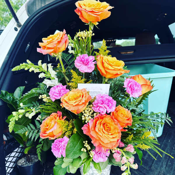 Orange roses and pink carnations arranged in a white vase