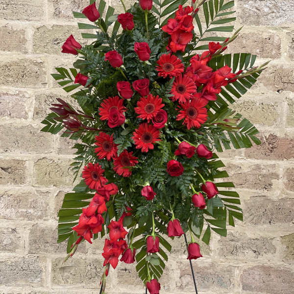 Red roses and gerbera daisies in a standing spray with greenery