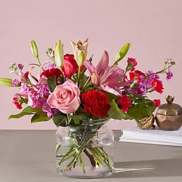 Mixed pink and red flowers arranged in a clear glass vase