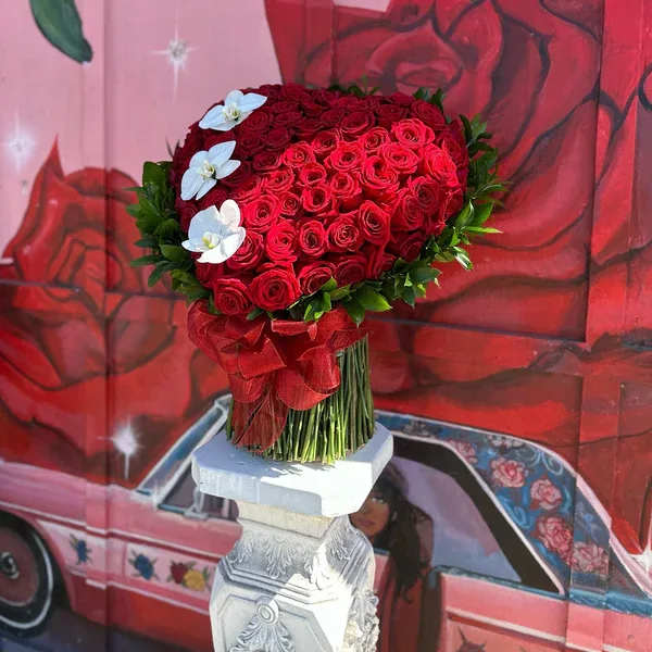 Heart-shaped bouquet of red roses with white flowers and a red ribbon