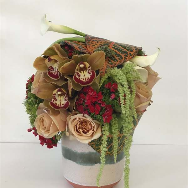 Bouquet of beige roses, orchids, and calla lilies in a ceramic vase