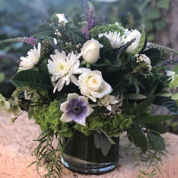 White roses and daisies in a glass vase with purple accents