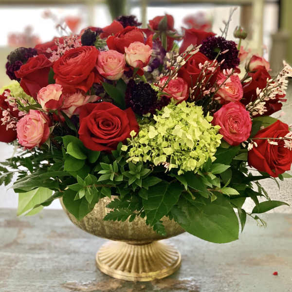 Red and pink roses arranged in a gold pedestal bowl