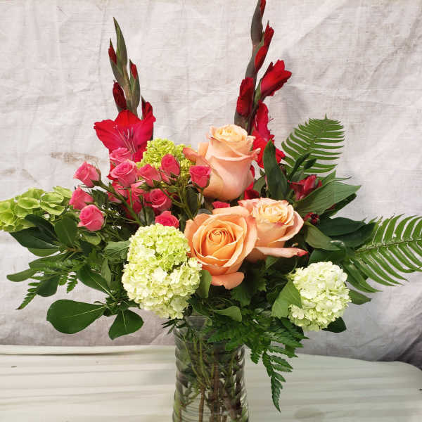 Mixed bouquet of peach and pink roses in a glass vase