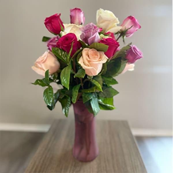 Bouquet of pink, peach, and white roses in a tall purple vase