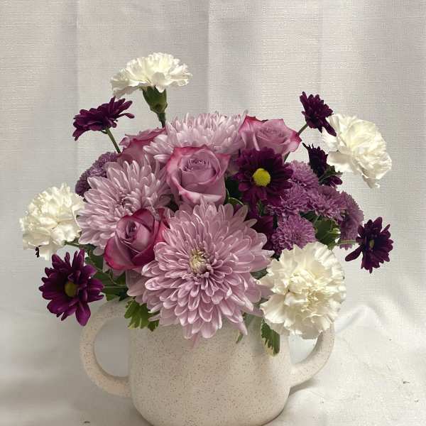 Pink and purple flowers arranged in a speckled white mug