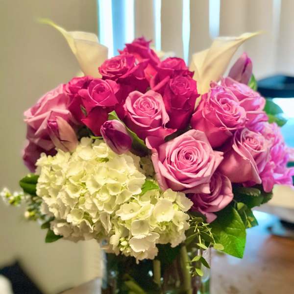 Pink and magenta roses with white hydrangeas in a glass vase