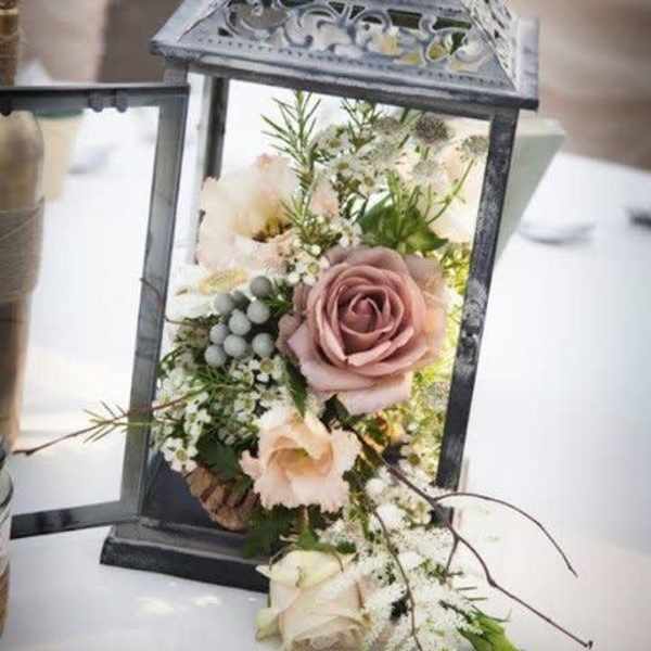 Lantern filled with pale roses and small white flowers