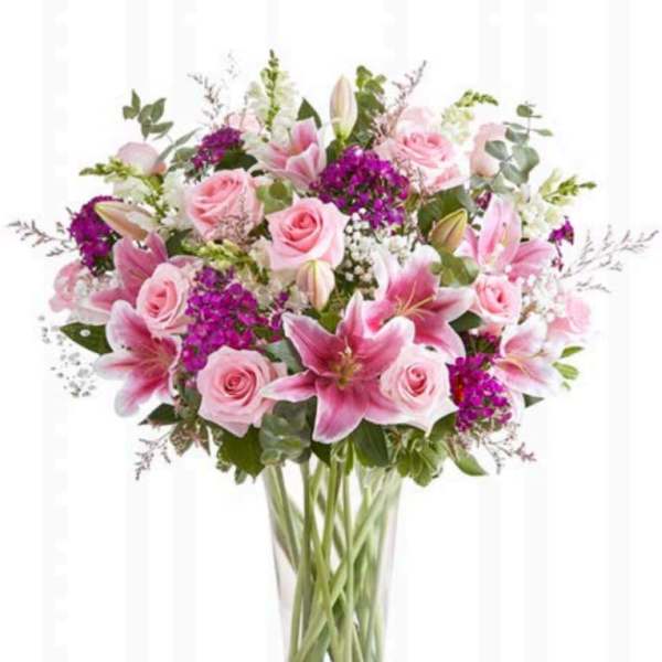 Pink roses and lilies arranged in a clear glass vase