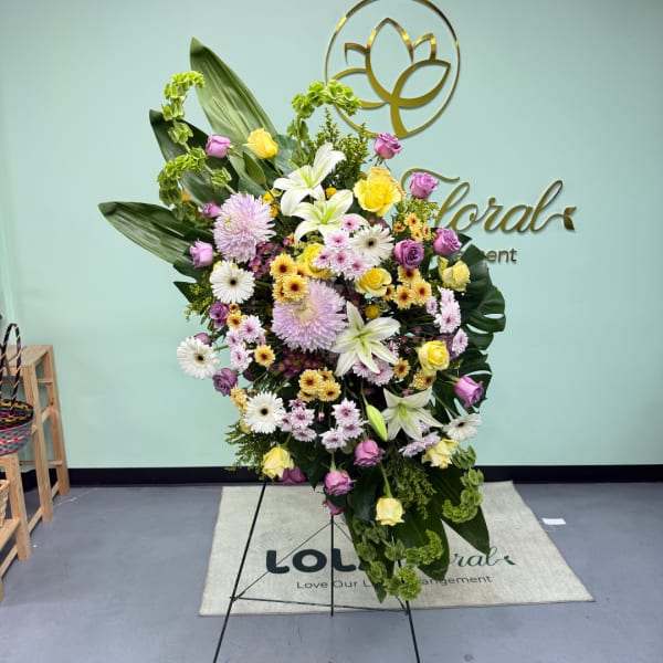 Large standing floral arrangement with lilies, roses, and daisies