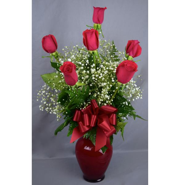 Red roses in a red vase with baby's breath and a ribbon bow