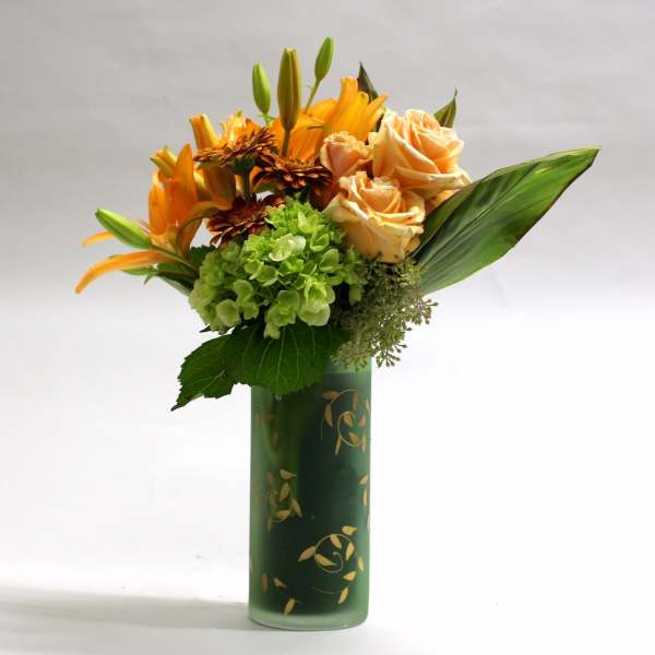 Orange lilies and peach roses arranged in a green vase