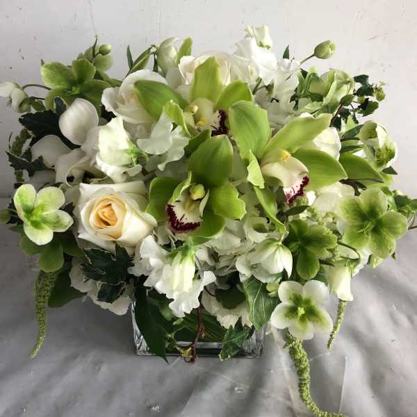 White and green floral arrangement in a square glass vase