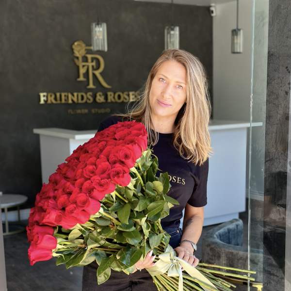 Woman holding a large bouquet of red roses tied with a ribbon