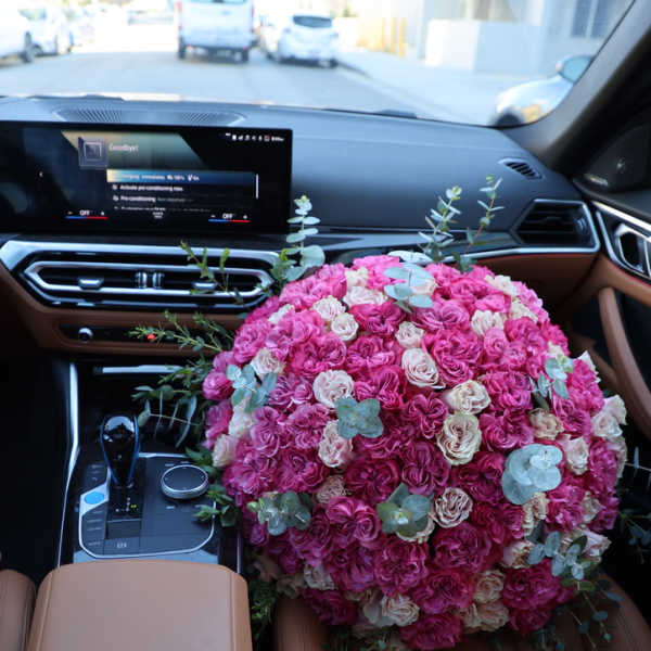 Large pink and cream rose bouquet resting on a car seat